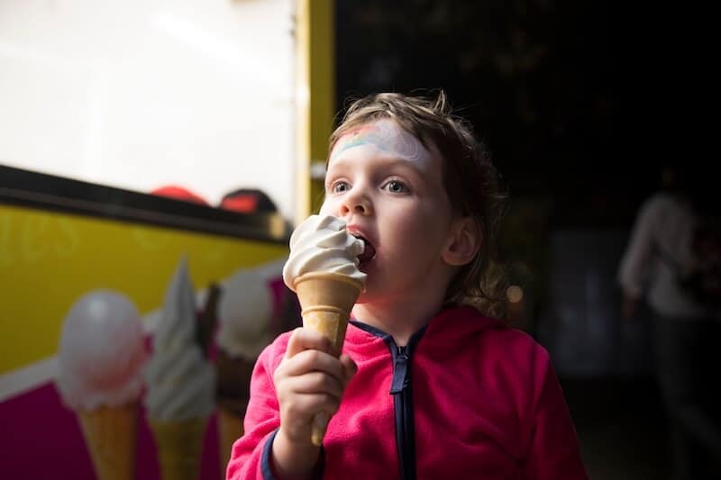 Young child eating vanilla flavour of ice cream.